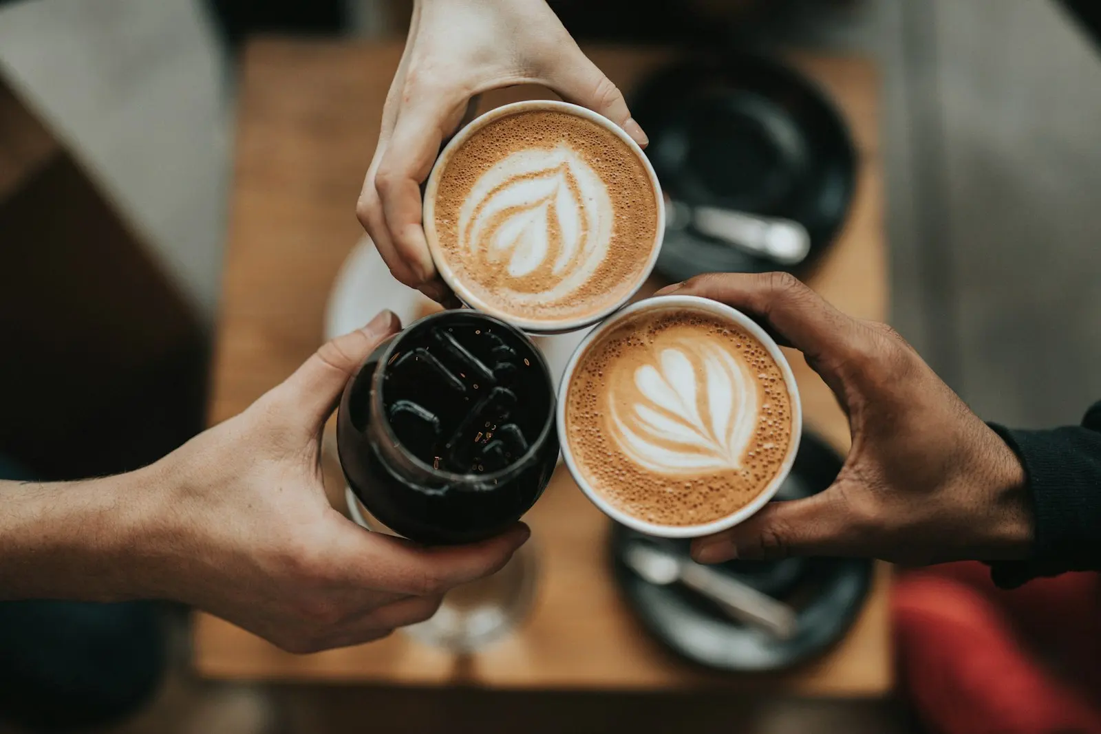 Two people clinking latte cups, seen from above
