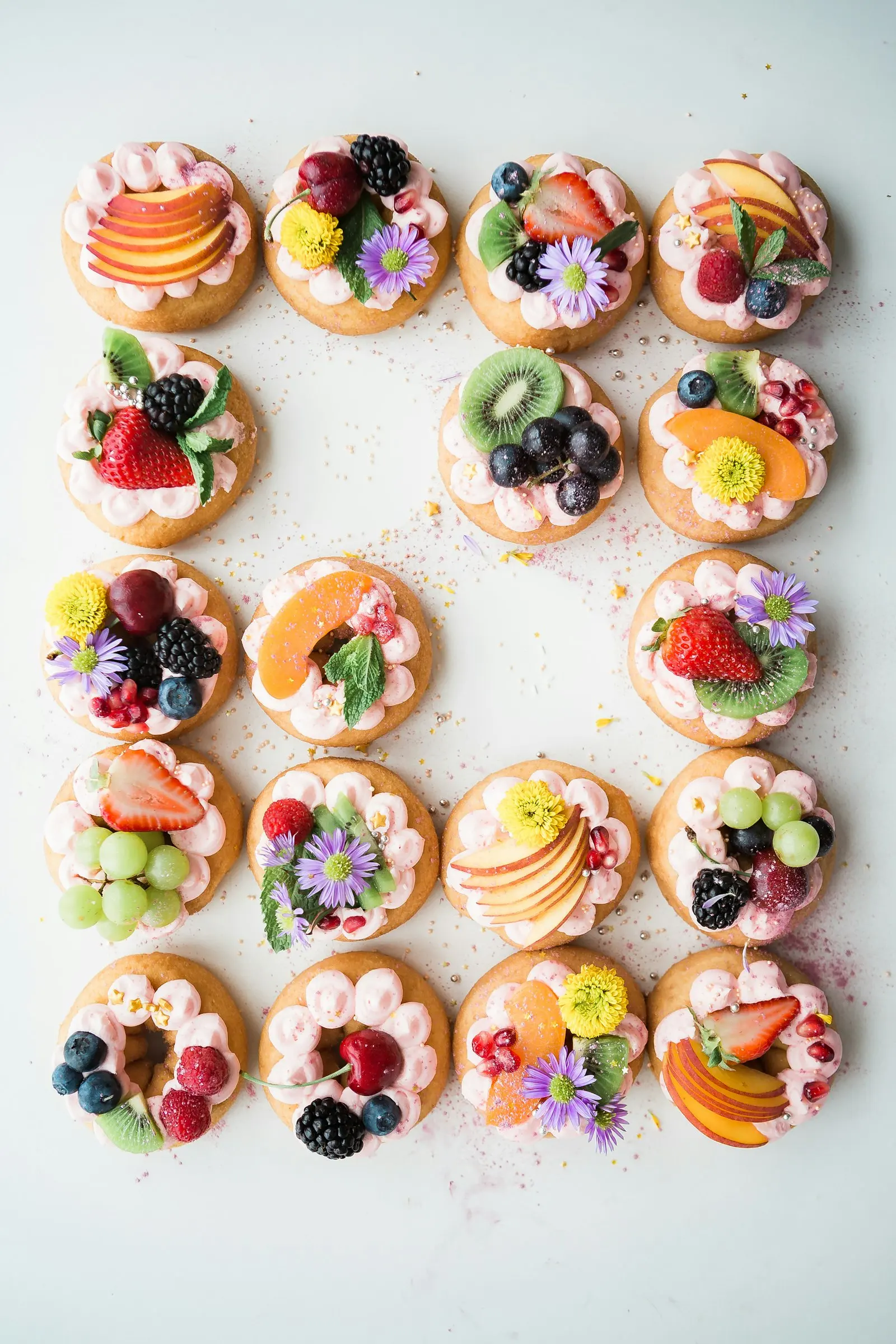 Fruit tarts lined up on a white surface, seen from above