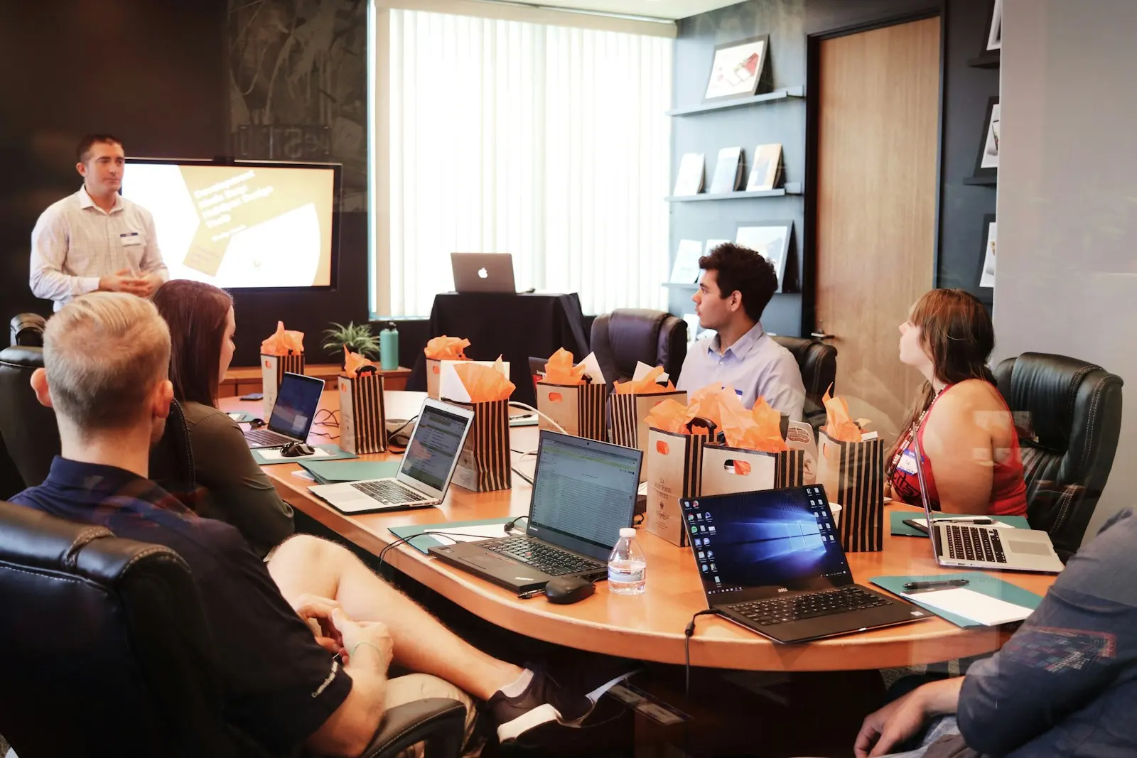 People around a conference table with laptops during a presentation