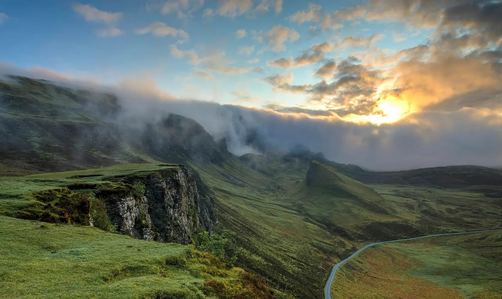 Green sea cliffs under low cloud at sunset