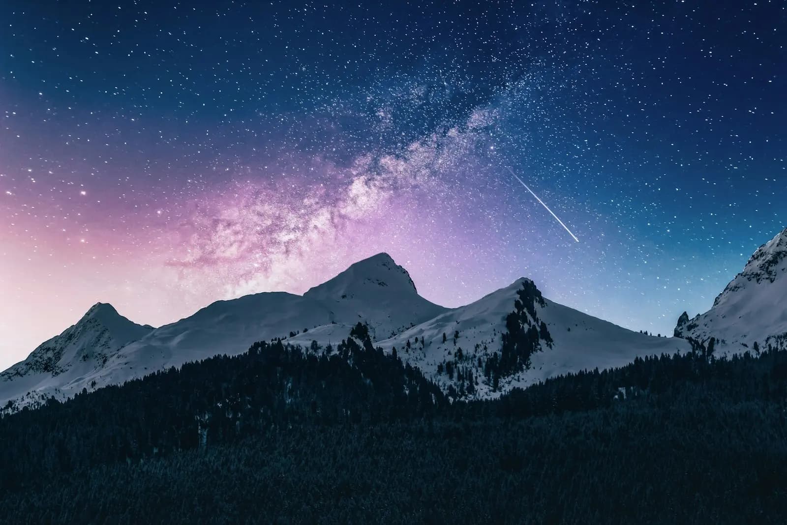 The Milky Way arching over snow covered peaks at night
