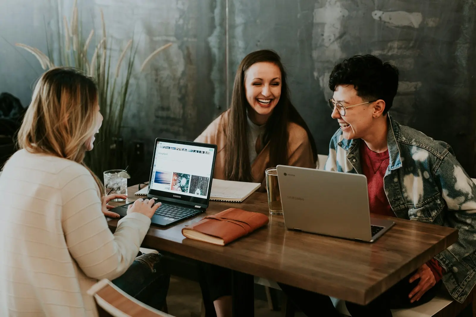 Students laughing together around laptops at a table
