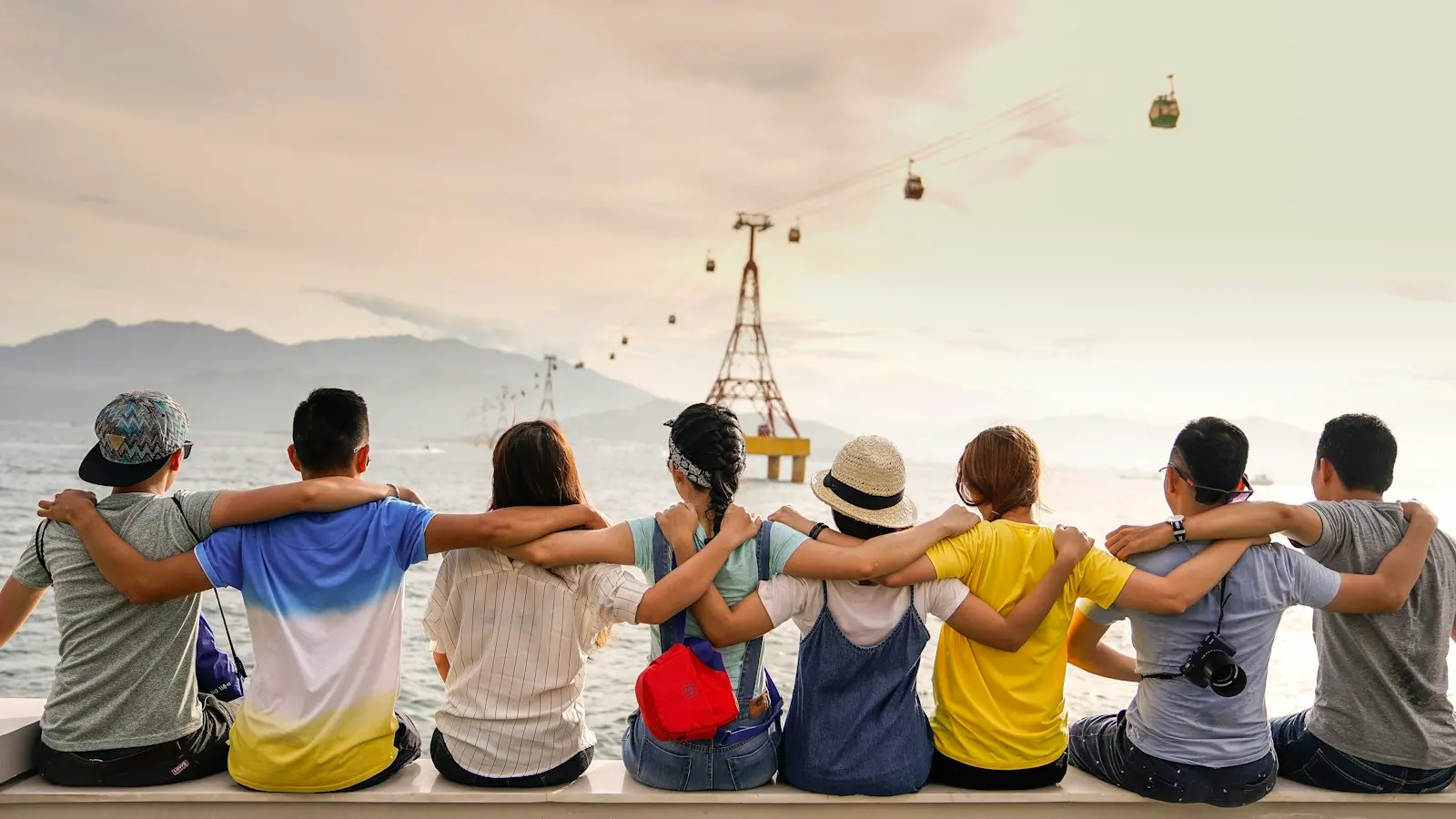 Friends sitting arm in arm facing mountains