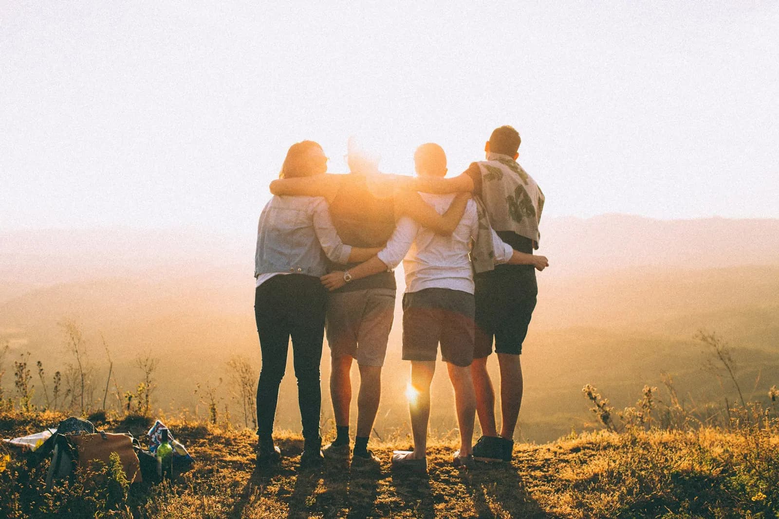 Friends hugging on a hill at sunset