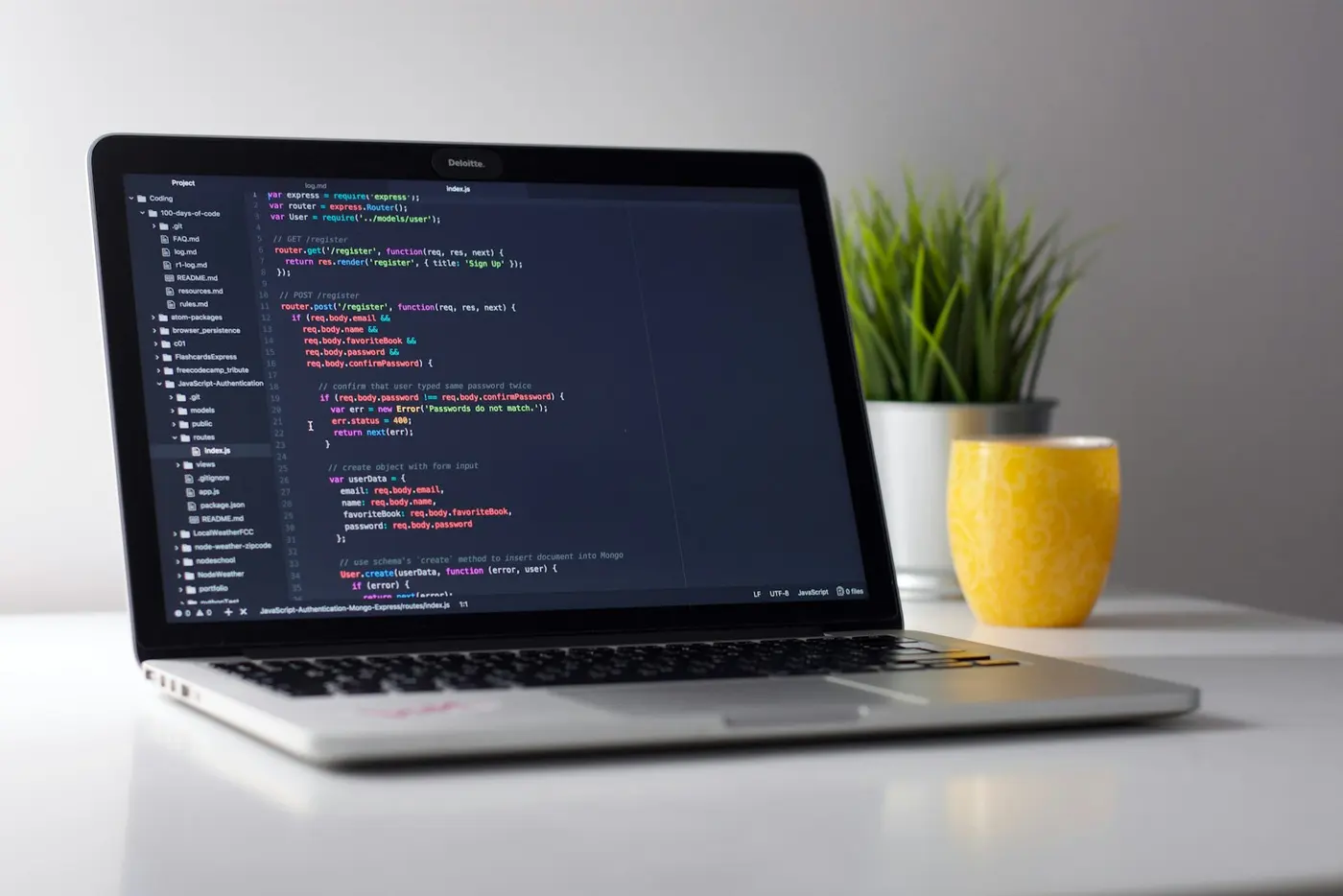 A laptop displaying code on a bright white desk